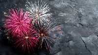 Vibrant pink and white fireworks exploding against dark stone background, creating festive celebration atmosphere for holiday events and special occasions.
