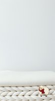 Cute sheep toy sitting on chunky knit blanket against neutral background, ready for nursery decor, children's product photography, greeting cards, and textile design projects.