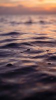 Soft ocean waves at golden hour with warm sunset colors reflecting on water surface creating peaceful seascape atmosphere for relaxation and meditation backgrounds.