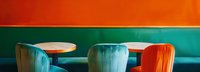 Modern cafe interior with vibrant orange and teal walls featuring plush velvet chairs and round wooden tables in retro style setting, creating bold color contrast.