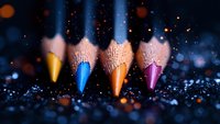Vibrant colored pencils lined up on dark glittery surface with bokeh lights and sparkles creating magical artistic atmosphere for creative design projects.