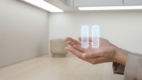 Hand holding transparent glass test tubes in modern laboratory setting for scientific research and medical testing applications.