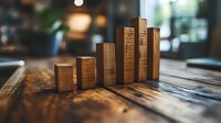 Wooden blocks arranged as ascending bar graph on rustic table with warm lighting, showing business growth concept for financial presentations.