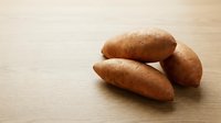 Russet potatoes arranged on light wooden surface, suitable for food photography, cooking blogs, recipe illustrations, and culinary content.