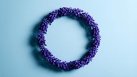 Purple flower wreath on light blue background. Circular floral arrangement with small violet blooms for spring decor, wedding invitations, greeting cards.