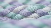 Braided rope with purple and green gradient colors in soft pastel tones creating textured pattern for craft and design projects.