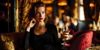 Elegant young Caucasian woman in black dress holding champagne glass in luxurious restaurant setting with warm ambient lighting for lifestyle and dining concepts.