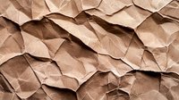 Crumpled brown kraft paper background with deep shadows and textured folds creating abstract geometric pattern. Natural recycled material surface.