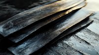 Dramatic close-up of raw black slate stone layers showing natural texture and mineral patterns. Dark moody lighting highlights rough geological formations.