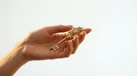 Hand holding ornate golden key with decorative handle against soft light background symbolizing success opportunity and unlocking potential.