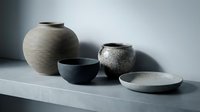 Handcrafted ceramic vessels with textured surfaces arranged on white shelf, featuring neutral tones for home decor and interior design styling.