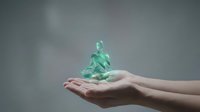 Glowing green meditation figure floating above open hands against gray background representing mindfulness, wellness and spiritual energy concepts.