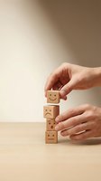 Hands arranging wooden blocks with emotional faces from sad to happy representing customer satisfaction and feedback management concepts.