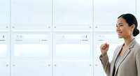 Asian female professional in beige blazer writing on whiteboard with grid layout, suitable for business, education, training, and corporate communication projects.