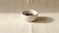 White ceramic bowl with star anise spices on neutral beige linen textile background for culinary cooking and food photography projects.