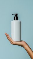 Female hand holding white pump bottle dispenser for skincare cosmetic product on mint green background for beauty and wellness branding.
