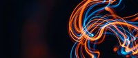 Dynamic orange and blue light trails creating flowing energy waves against dark background for modern digital design projects.