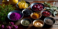 Colorful spices, powders and seasonings in ceramic bowls on rustic wooden table with fresh herbs, citrus slices and dried flowers for natural cooking.
