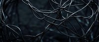 Abstract dark metallic wires tangled in chaotic pattern creating modern industrial texture for technology and connectivity concepts in graphic design.