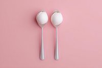 Two silver spoons with white cotton candy on pink background, minimalist food photography composition for dessert menu or sweet shop advertising.