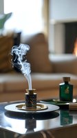 Elegant incense stick burning in ornate holder with white smoke swirls rising on glass table in modern living room interior for relaxation and aromatherapy.