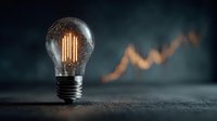 Glowing vintage light bulb with warm filament against blurred financial growth chart background symbolizing innovation and business success concepts.