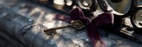 Vintage brass key with burgundy velvet ribbon lying on aged book in dramatic lighting, creating nostalgic and romantic atmosphere. Decorative antique details.