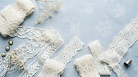 Vintage white lace trims, ribbons and decorative elements arranged on soft blue background for crafting, sewing and DIY wedding projects.