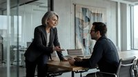 Professional mature businesswoman mentoring young male colleague in modern office meeting room discussing documents and strategy.