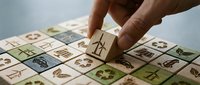 Hand placing wooden cube with recycling symbol on eco-friendly grid pattern showcasing environmental sustainability concepts for green business practices.