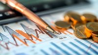Financial chart analysis with golden coins and copper pen on business report showing market trends and investment data for economic forecasting.