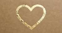 Heart shape drawn in wet sand on beach shore with golden sunlight reflection creating romantic seaside love symbol for Valentine's Day greeting cards.