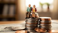 Miniature elderly couple figurines sitting on stacked coins representing retirement savings, pension planning and financial security for senior years.