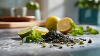 Fresh tea leaves with lime and lemon slices on marble countertop, herbs and ingredients for brewing aromatic tea or preparing natural remedies.