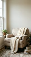 Cozy reading nook with a beige armchair, chunky knit blanket, open book, houseplants, and warm natural light by a window.