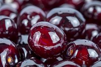 Fresh ripe dark red cherries in macro view showing glossy surface and natural texture, wet with water drops. Suitable for food industry and healthy eating concepts.