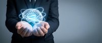 Businessman in suit holding glowing digital brain with atomic orbital rings above open palms representing artificial intelligence and innovation concepts.