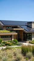 Modern eco-friendly house with solar panels on roof and sustainable landscaping under clear blue sky for renewable energy and green living concepts.