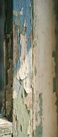 Weathered wooden surface with peeling paint layers in blue, green and white creating vintage texture for restoration and design projects.