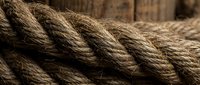 Thick natural jute rope coils with detailed fiber texture against rustic wooden background for nautical and craft projects.