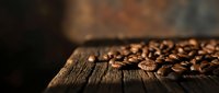 Roasted coffee beans scattered on rustic wooden surface with warm lighting creating cozy cafe atmosphere for beverage and food industry marketing.