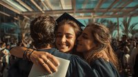 Young female graduate in cap and gown embraced by family members during commencement ceremony, celebrating academic achievement with joy and pride.