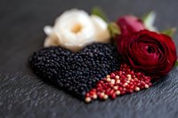 Heart shaped black caviar with pink peppercorns and red rose on dark slate background, romantic gourmet food styling for luxury dining and valentines.