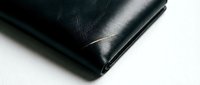 Black leather wallet corner detail showing premium craftsmanship and elegant stitching on clean white background for luxury accessories design.
