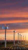 Wind turbines generating renewable energy at sunset with digital grid overlay representing smart technology and sustainable power infrastructure.
