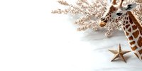 Elegant giraffe figure with golden star and glittering branches on white background, creating minimalist holiday composition. Perfect for festive designs.