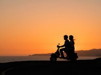 Silhouette of couple riding scooter at sunset by ocean, romantic travel and adventure lifestyle scene for leisure and vacation concepts.