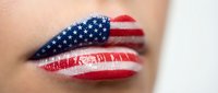 Patriotic lips painted with American flag design featuring stars and stripes in red white and blue for Independence Day celebration makeup.