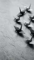 Paper origami cranes arranged in formation on textured surface creating minimalist black and white composition for meditation and mindfulness concepts.