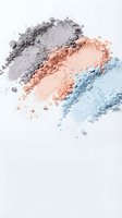Colorful crushed eyeshadow powder in purple, coral and blue shades scattered on white background for makeup and beauty cosmetics applications.